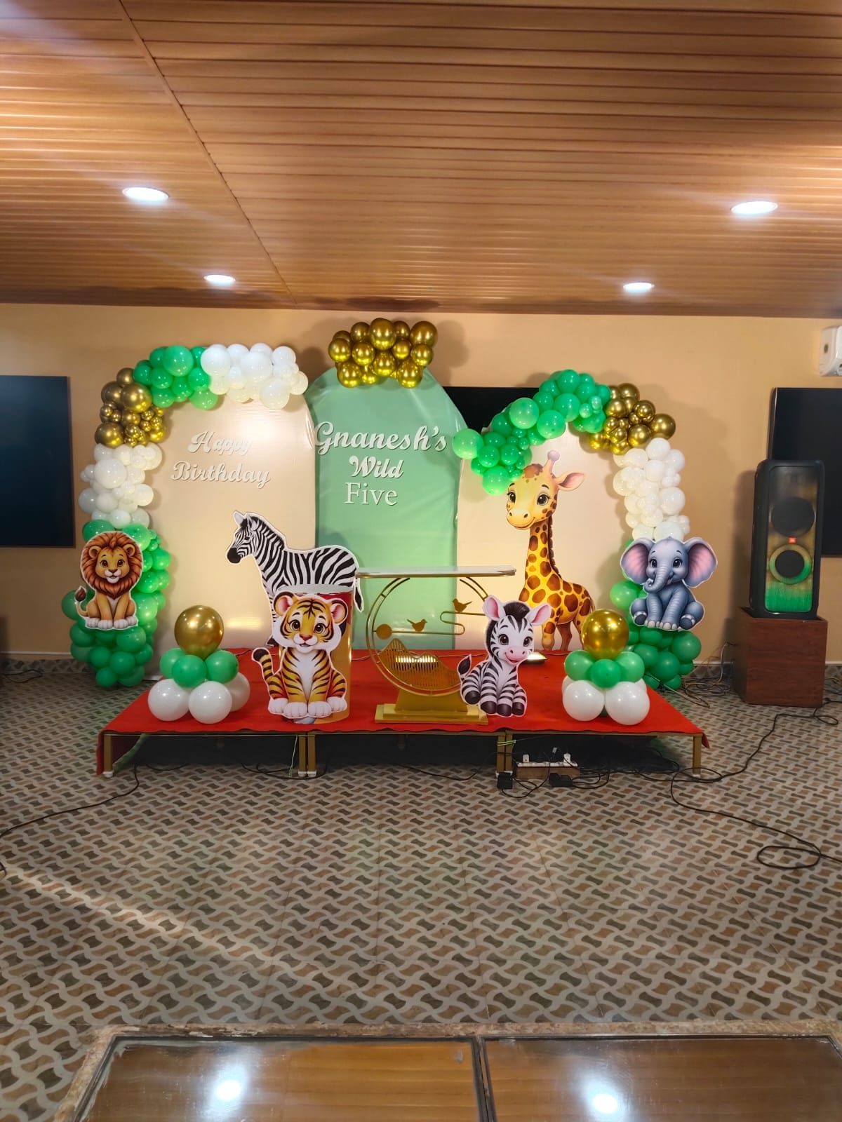 Jungle-theme kids’ birthday stage with balloon arches and animal cut-outs