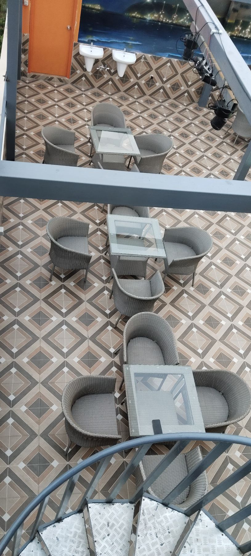 Wicker chairs and glass tables — seating area at The View rooftop