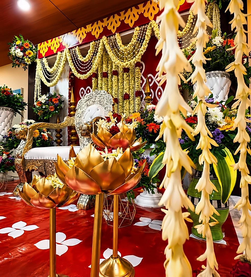 Close-up of traditional stage décor — brass lotus lamps and jasmine garlands